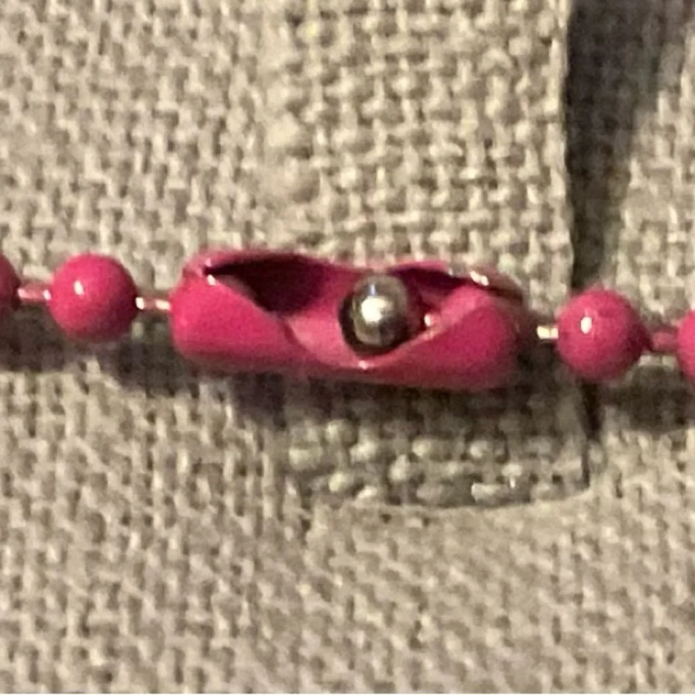 Hello Kitty :Kitty face slightly angled on a bight pink beaded necklace blue bow